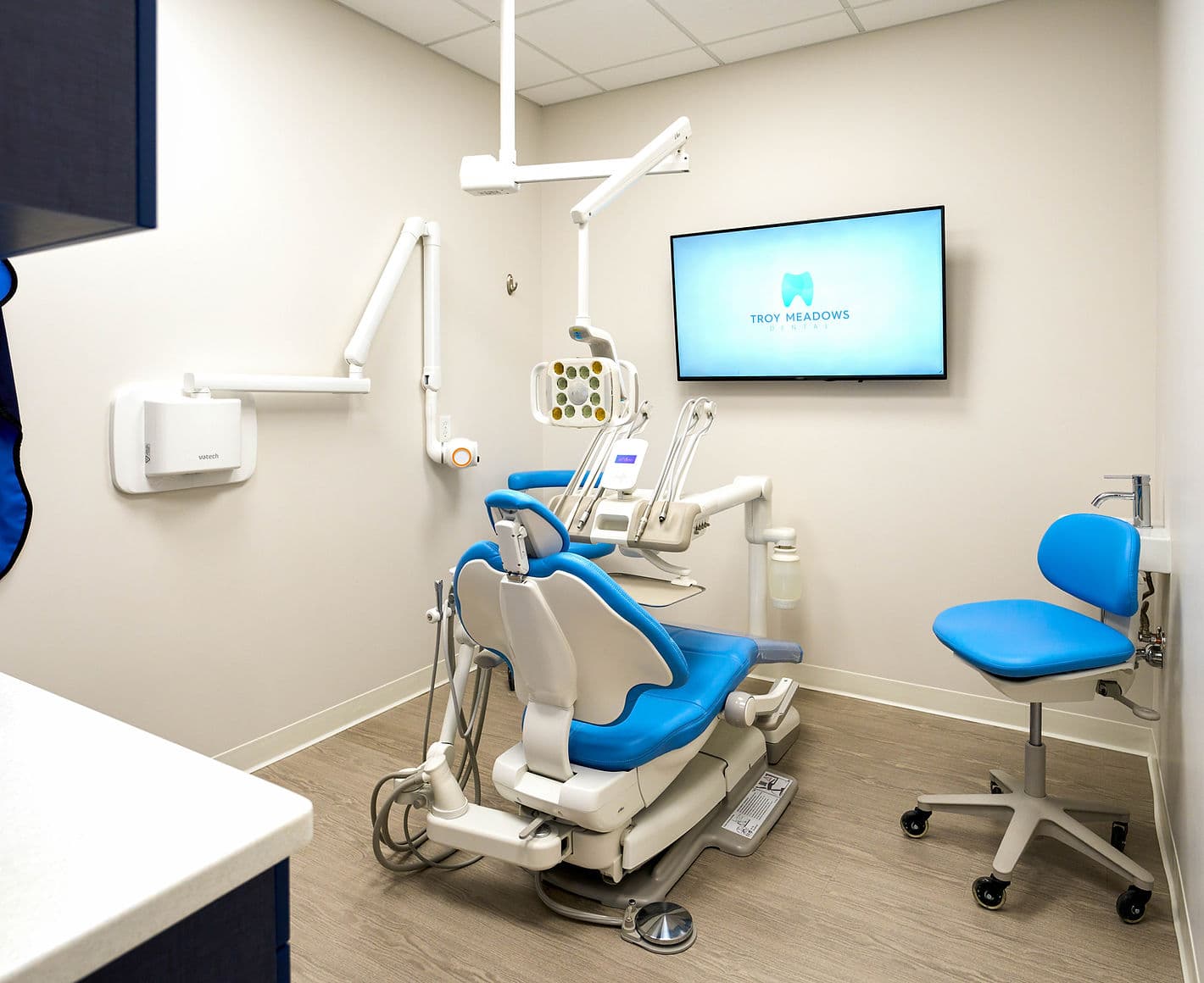Modern treatment room at Troy Meadows Dental with a blue dental chair